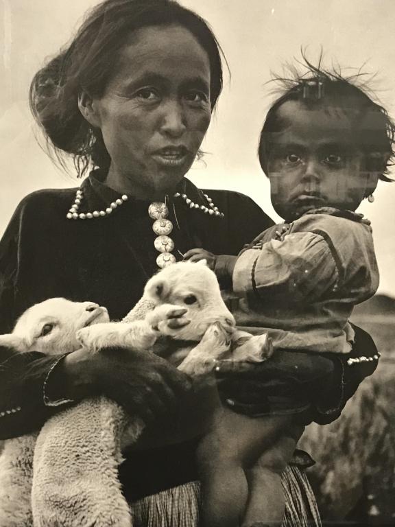Framed Poster, The Photographs Of Laura Gilpin Framed: Framed black and white poster depicting Laura Gilpin’s ‘Navaho Woman, Child and Lambs,’ originally produced as a platinum print in 1932. Print is matted and set behind glass in black tone metal