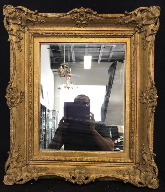 Vintage Gold Toned Ornate Mirror: Mirrors frame is wooden and gold toned. Frame is ornately detailed. Contains some chips. Possibly antique. Measures approx 27 inches tall 24 inches wide.