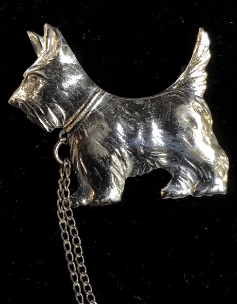 Sterling Silver Scottie Dogs Sweater Chain Clasp: Silver silver metal Scottie dogs sweater chain clasps, pins, brooches. Three Scottie dogs are joined by chain ‘leash.’ Underside of one dog is marked for sterling. Each dog measures approx 1.25 in