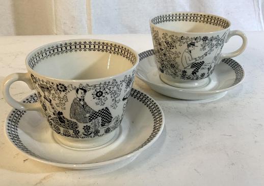 PAIR CERAMIC GIANT MUGS AND PLATES: Pair of mugs and plates. Made from company Arabia located in Finland. Cups and plates have black ink printed designs. Cups measure approximately 3.5 inches in height and 4.5 inches in diameter. Plates