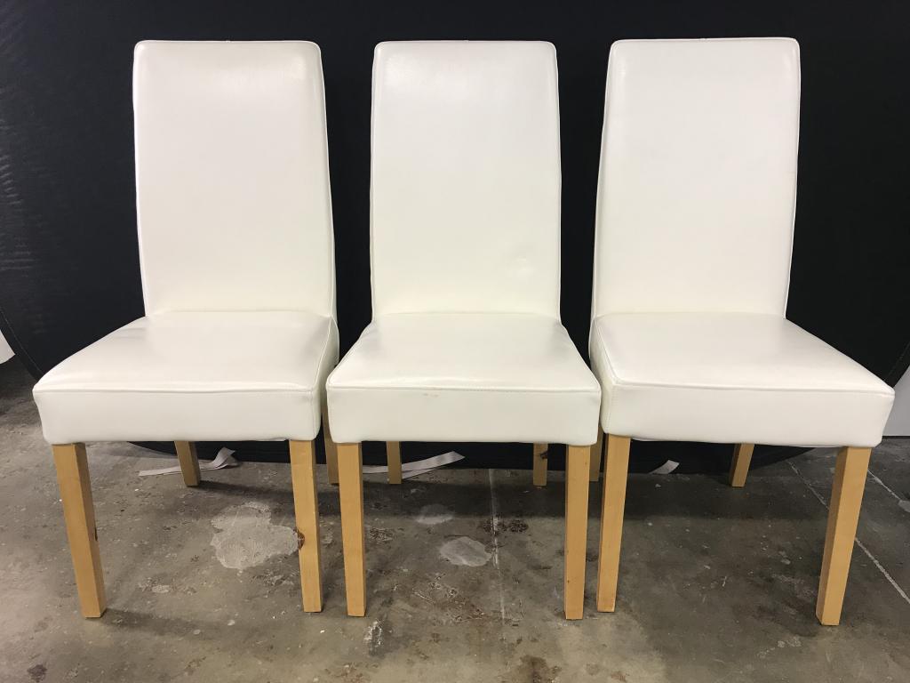 Set 3 White Toned Side chairs: Lot includes 3 white toned side chairs in the style of real leather. Each have 4 tan toned legs. Pieces measure approx 39 inches tall 18 inches wide 22 inches deep. Pieces have some wear may need some