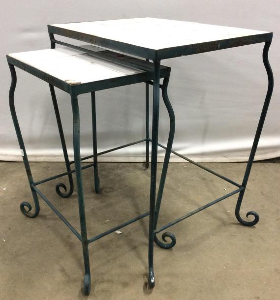 Set 2 Outdoor Tiled Metal Nesting Tables: Lot includes 2 Nesting tables. Each are green toned & Metal. Top of each table is white toned and tiled. Feet have c curve detail. Largest pi3c3 Measures approx 22 inches tall 19 inches wide 14 inches