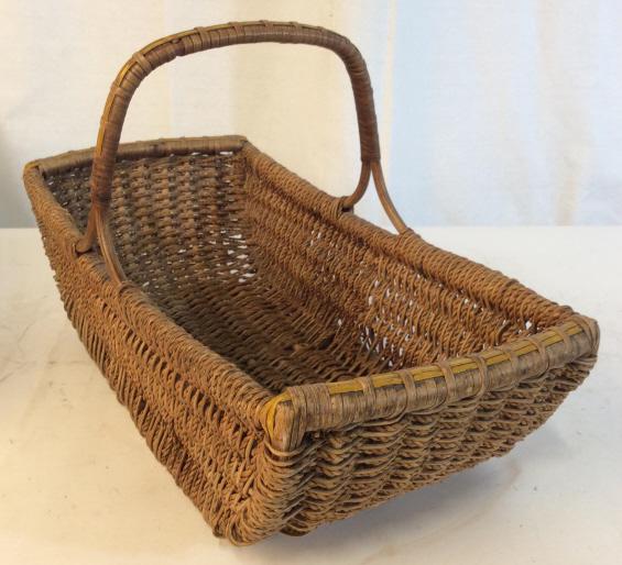 Vintage woven basket: Woven basket has one handle. Slight nicking of the woven material is evident. Basket measures approximately 17 by 8.5 inches. Height without handle is approximately 5 inches. Golden brown in color. Wo