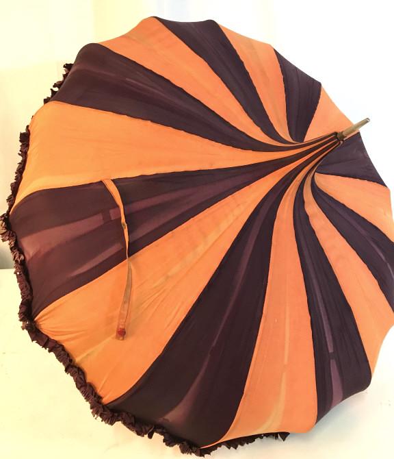 VINTAGE PAGODA UMBRELLA ORANGE AND MAROON: Orange and maroon colored pagoda umbrella. Thin handle and metal hardware. Measures approx 34 inches long. Umbrella skirt has ruffles at the bottom. Needs to be cleaned. May be slight rusting and some