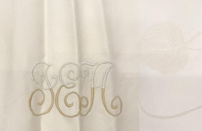Cream Color Leaf Motif Tablecloth: 64 x 124in. approx. Cream color. Center is monogrammed with ‘ TEA’ (looks like a T or J). No discolorations noticed. No rips or loose threads noticed. Appears to have been dry cleaned. Table linen