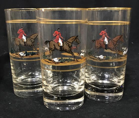 Set 3 Vintage Racing Horse Tall Drinking Glasses: 3 tall drinking glasses depicting a man on a horse following two dogs chasing a fox. No evident branding or trademarking. Gold colored rim. Glasses need cleaning. Designs seem to have been painted on.