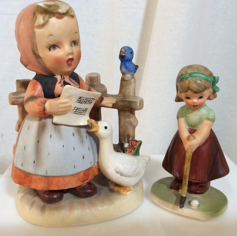Lot 2 Hummel Style Ceramic Figurines: Lot 2 Ceramic Figurines in the style of Hummel Figurines. Lot includes girl with duck and music Sheet, marked on underside with crossed arrows and number 8082, and Girl playing golf, marked on undersi