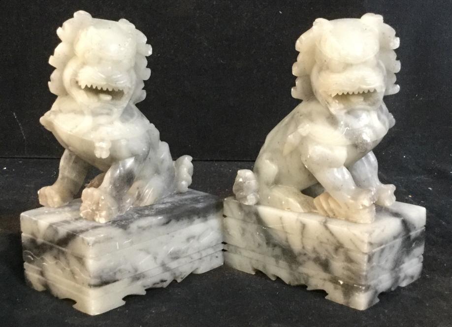 Pair Carved Natural Stone Chinese Foo Dog Figurals: Early 20th century, circa 1920-1930s Carved Stone Temple Guardian Foo Dogs, Stone possibly soapstone, marble or alabaster. Black & White toned stone. Plinth base measure 3 1/4 x 2 x 1 3/8 in. Scallop 