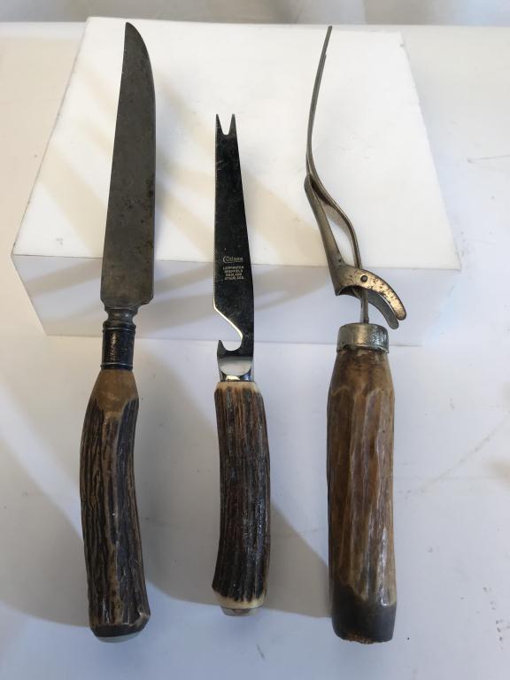 Lot 3 Utensils W Horn Handles: Lot includes 1 knife, 1 serving/carving fork with stand, and 1 fork tipped knife with opener. The fork tipped knife is marked for Cutlass Leppington Sheffield England Stainless. Utensils have horn han