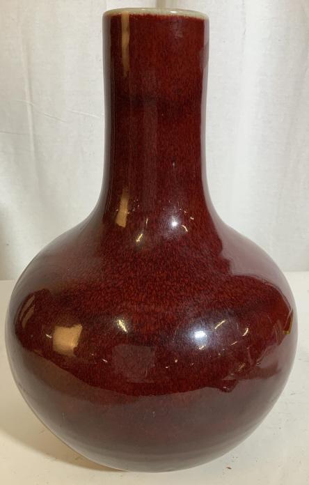 Vintage OXBLOOD CHINESE CERAMIC VASE: Chinese vase in color Ox Blood. Stands approximately 14.5 inches tall and is approximately 11 inches wide. Circular body that tapers into a tube shape. Not signed. Evident wear on the bottom. Chinese 