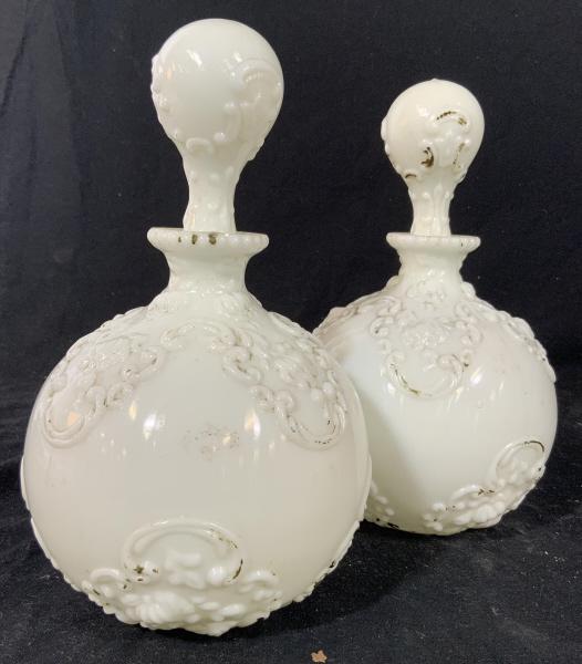 Pr Antique Milk Glass large Bottles C1880: 19th Century milk glass with articulated raised swirl and swag pattern, each w stopper, collectible antique decorative arts, tableware, dresser accessory, each measures app ht 10 inches diameter app 6