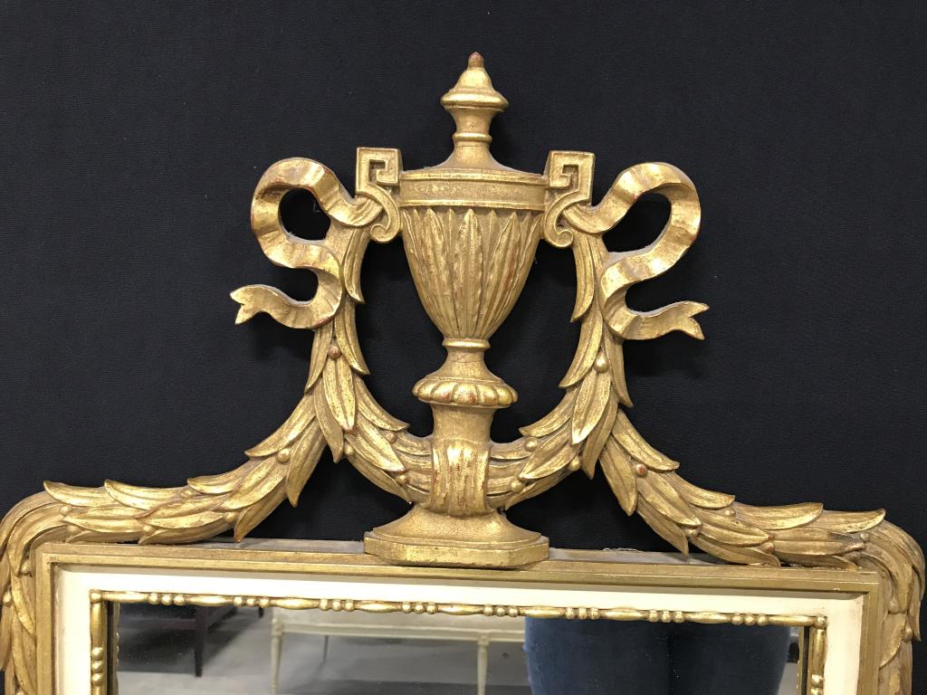 D. Milch & Sons Gilt Urn-Top Pier Mirror: Verso marked for D. Milch & Sons. Piermirror Set In Carved Wood Style Frame With Urn And wreath pediment top and wreath details on bottom. Measures approx 54 by 22.5 in . Pier mirror, gilt mirror, urn