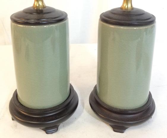 Pair Green Toned Porcelain Lamps: Lot includes 2 lamps. Each are green toned & porcelain with black toned footed bases. Each measures approx 10.5 inches tall 4 inches wide. Each piece has crazing. home lighting and decor, table lamps,