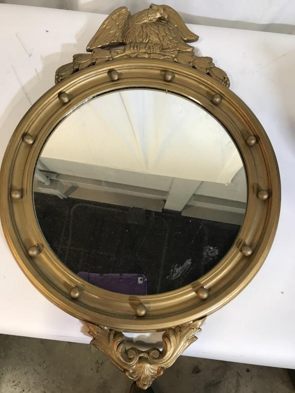 Carved American Eagle Gold Tone Round Mirror: Vintage, Hand finished Regency Eagle Accent Mirror in Gold Leaf. Syrocco Style Carvings. Wired and ready to hang. Paper covered backing. Accented by a studded ball design on the ‘wheel’. Measures