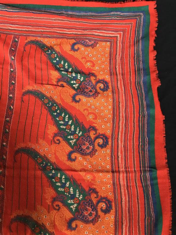 Red Paisley Cotton Gauze Scarf: Very large scarf with edge fringes, 45 x 44.5 in. Semi transparent, soft and glaze like. Decorated with large paisley images and repetitive colorful lines. Background ogre- red. No rips or pulls, no m