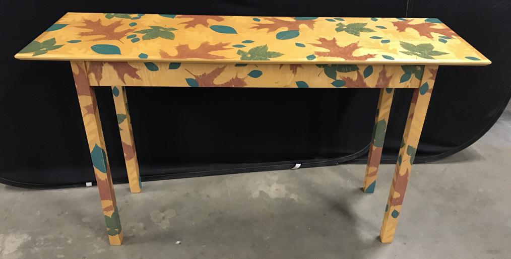 Maple Toned Wooden High Table W Leaf Design: Vintage Maple Toned Wooden High Table With Leaf Design, Leaf Design in green, brown and gold toned painted leaves, illegibly signed on underside by artist’s hand, dated 1/95, measures approximately