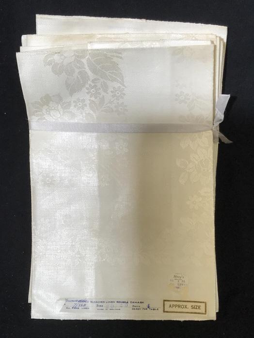 Lot 17 White Vintage Damask Napkin Linens: Two different sets. 5 blossom design cotton/ ration damask napkins. Some areas yellowed from age and use. 16 x 20 in. Other set, 12 floral pattern damask 20 x 20 in. Label reads ‘ Hemmed Bleached Li