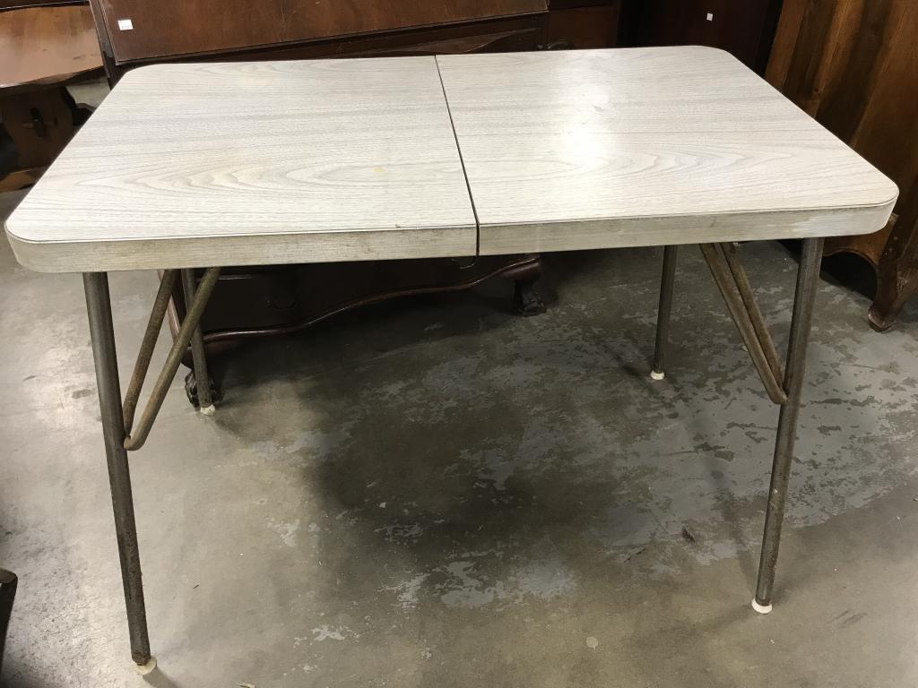 Vintage Retro Atomic Era Kitchen Table: Kitchen table sits atop metal legs. Tabletop has metal banding with gray tone wood style hard laminate top. Table comes with extension leaf insert. Measures approx 30.25 inches in height by 39.5 inche