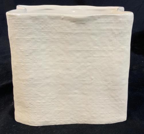 Textured Glazed White Ceramic Vase: Vessel, tableware, label reads que, exploring new spaces, measures ht app 8 inches width 8 inches depth app 4 inches shelf peice, decorative arts