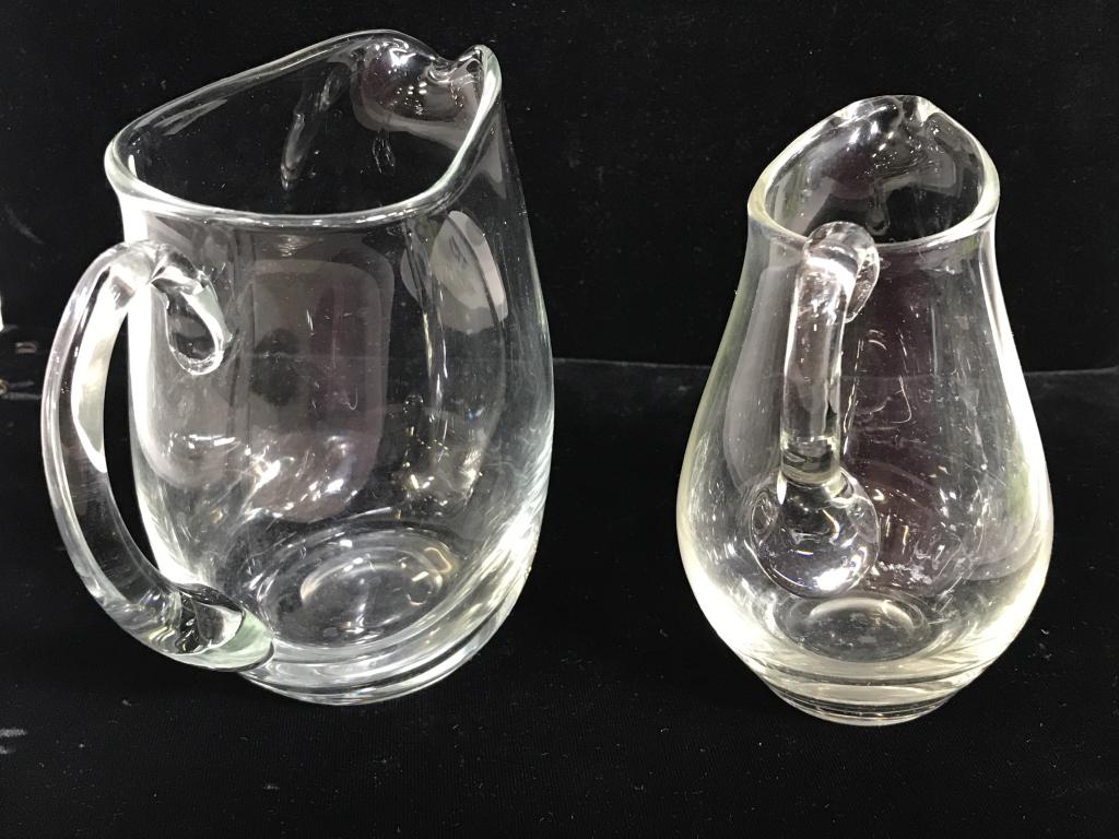 Lot 6 Glass Server Tableware: Two creamer pitchers, 1 vintage ashtray, 1 covered Pyrex butter dish, 1 art glass bowl and ladle spoon. Bowl has chip on rim. Larger serving pitcher measures 5 x 5.5 x 3 in. Some wear surface marks on