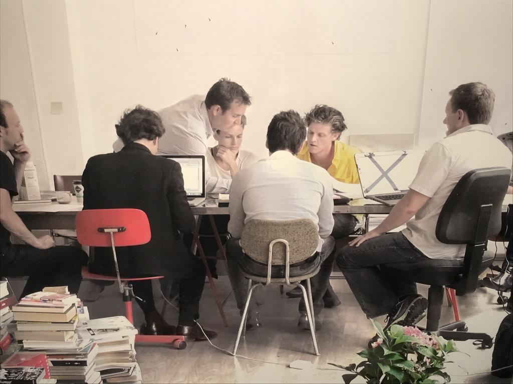 Framed Lithograph, Scandi Co-Working Interior: Framed Lithograph Of Photograph Of interior of Scandinavian style working environment. Possibly an offset lithograph. Print is set behind plexiglass in white tone wood frame. Measures approx 16.5 inch