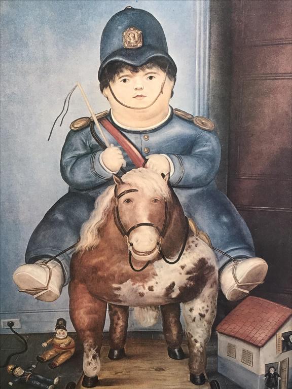 Framed Fernando Botero Poster: Framed poster for Fernando Botero, featuring child on play horse with ‘Botero’ typed along bottom. Poster is set behind glass in silver tone metal frame. Measures approx 14.5 inches in height by 1