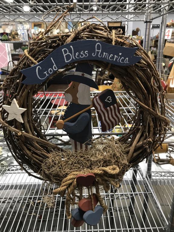 Branch Wreath with Carved Wood uncle Sam Figure: Painted carved wood objects- stars, American Flag, Hearts, Patriotic Vintage UNcle Sam And Sign that reads ‘God Bless America’. Approx 15.5 in. diameter. Has a wire make shift hook for hanging. Ha