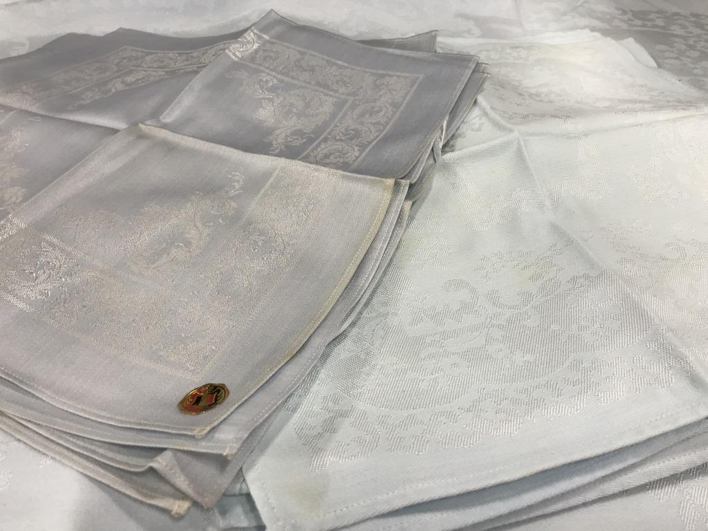 Lot 15 Cotton Tablecloth, Napkins: Baby blue tablecloth with traditional scroll design and 8 matching dinner napkins. A light blemish on some napkins. Tablecloth 92 x 54 in. Approx. Does have a hole/ rip in fabric toward end, measured 