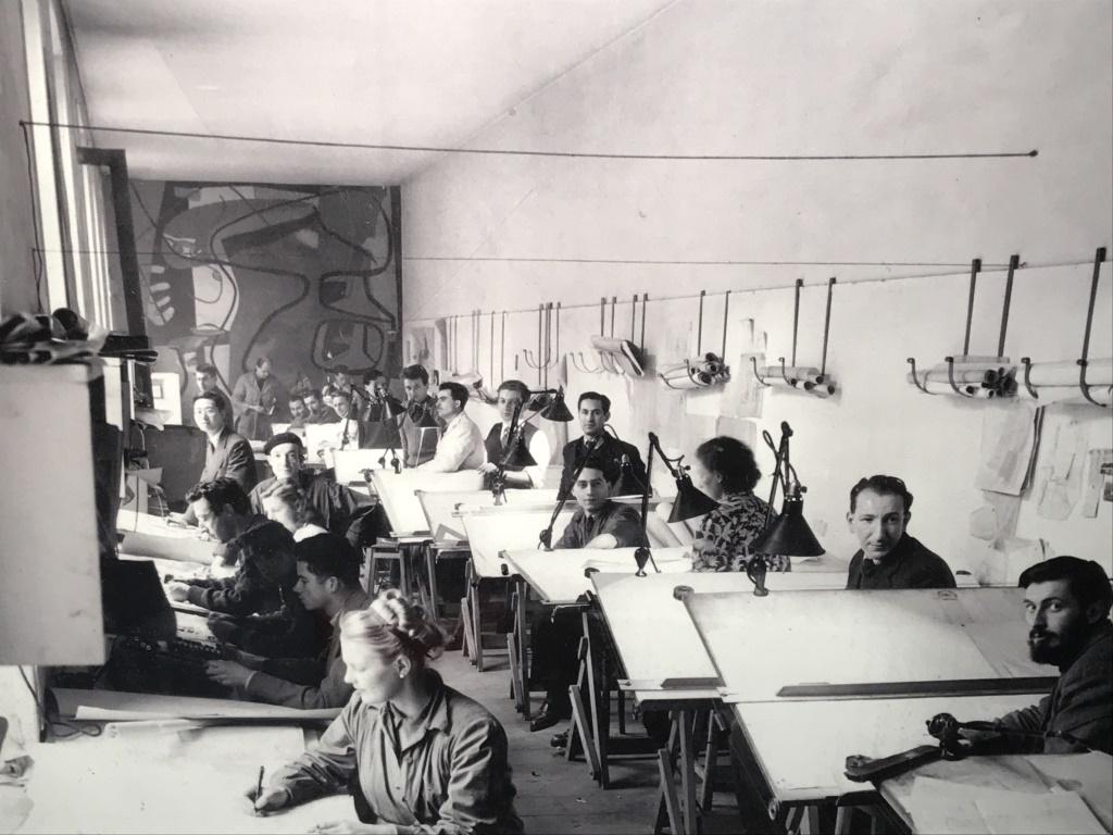 Framed B&W Lithograph, Le Corbusier's Atelier: Vintage black & white tone lithograph depicting interior of Le Corbusier's atelier at 35 rue Sevres. Possibly an offset lithograph. Print is set behind plexiglass in white tone wood frame. Measures ap
