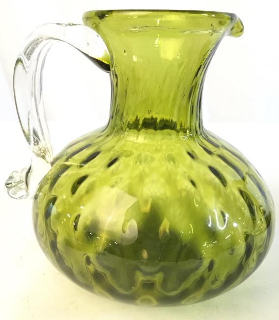Green Toned Art Glass Pitcher: Pitcher is green toned with clear handle. Art Glass Pitcher, Glass Pitcher, Green Pitcher, art glass tableware, decorative arts and crafts. Piece measures approx 6 inches tall 5.5 inches wide. 6
