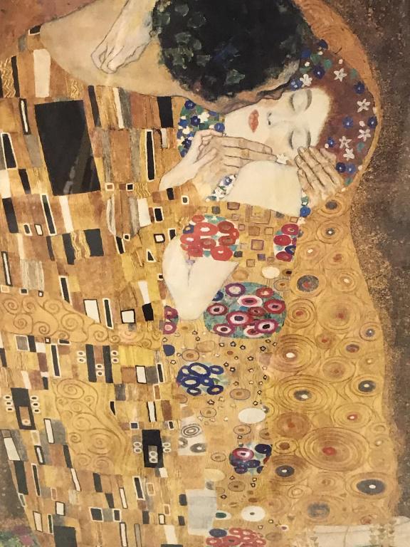 Framed Poster, Klimt’s The Kiss: Framed poster print of Gustav Klimt’s The Kiss. Print is double matted and set behind plexiglass in gold tone wood composite frame. Measures approx 36 inches in height by 30 inches in width with fra