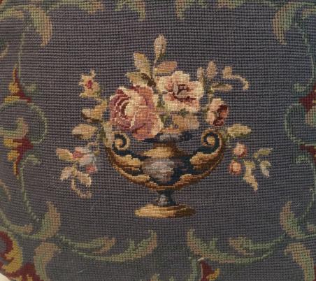 Cross stitch Toss Pillow: With Urn And floral design, tones of blue greens and reds, dark rust red fabric back panel. One corner has possibly been repaired, sewn at a different angle. Measures approx 15 in by 15 in, toss pillo