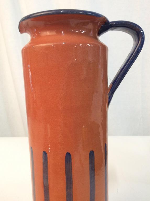 Tall ceramic Drinks Pitcher: Burnt orange toned with blue toned trim and line details , crazing to glaze, chips to rim largest near handle, 10 in by 5 in by 3 in . drinks pitcher, tableware, kitchen accessory, 4