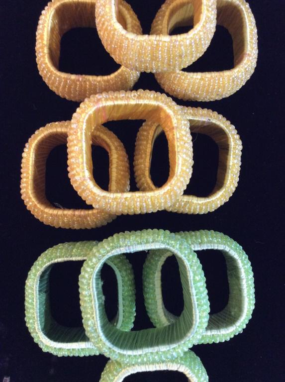 Set 16 Vintage Hard Form Beaded Napkin Rings: 12 yellow, 4 green, monochrome. Woven beads on string, wrapped around a rounded corner square Napkin Ring. Just shy of 2 x 2 in. Pass- through measurement 1 3/8 in. No loose beads. Napkin Rings, Beade