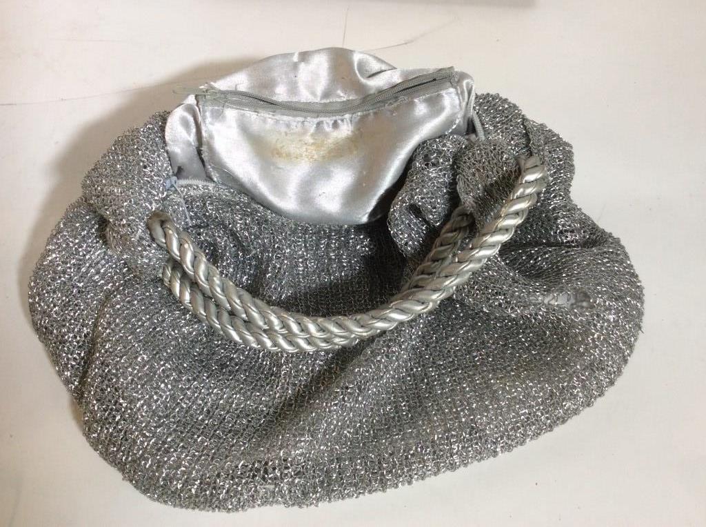 Vintage Silver Mesh Handbag: Firm rope handles, hang approx 6 in. Silver mesh fabric and interior lining. Some discoloration and wear in interior lining and a rip on the outside, can be mended. Body of bag9x 13 in. approx. Mesh P