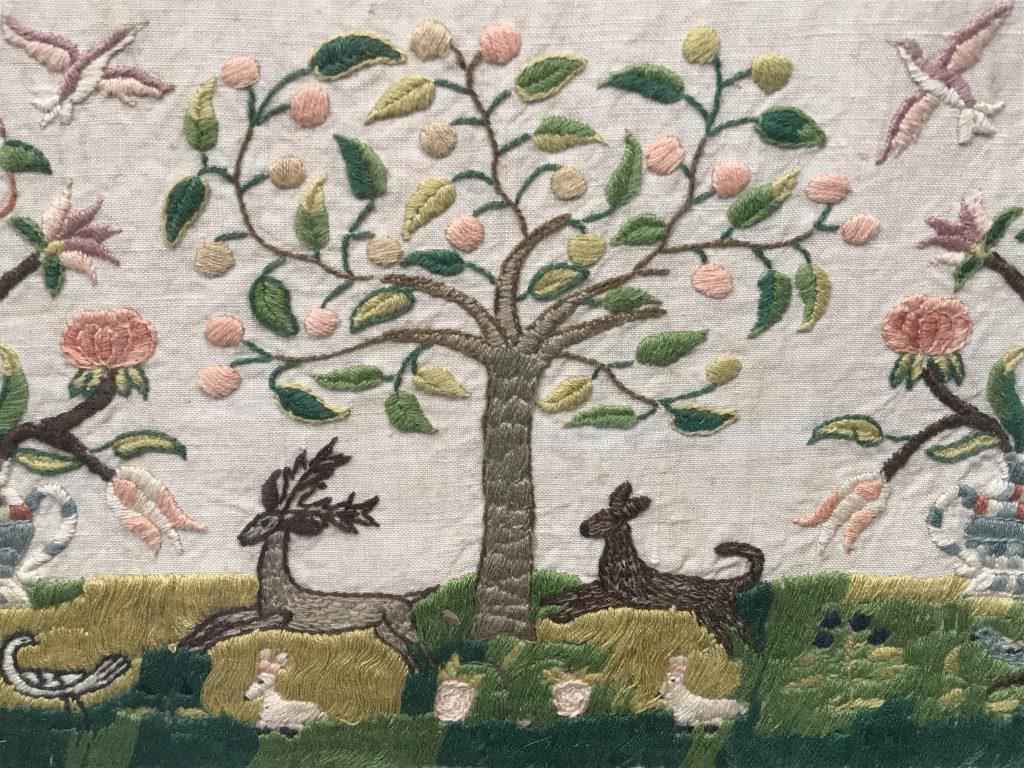 Intricate Needlepoint Sampler W Forest Motif: Vintage, possibly antique, Needlepoint Sampler with alaphabet and numbers along top, intricate garden forest scene with deer and birds. Sampler is set behind glass in wood frame. Measures approximatel