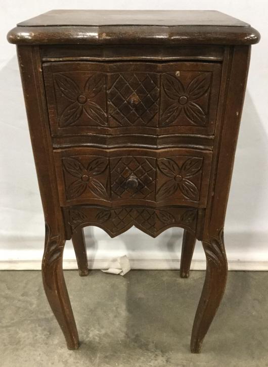 Petite Carved Wooden End Table W Drawers: End table is brown toned and wooden. Piece has 2 drawers. Contains carved wooden detail. Measures approx. 25 inches tall 12.5 inches wide 10.5 inches deep. piece is missing top drawer handle. end tabl