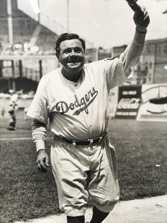 Framed B&W Babe Ruth Photo Print: Framed photo print in black and white depicting Babe Ruth in Brooklyn Dodgers uniform. Photo is set behind glass in wood frame. Measures approximately 11 inches in height by 8 inches in width with fra