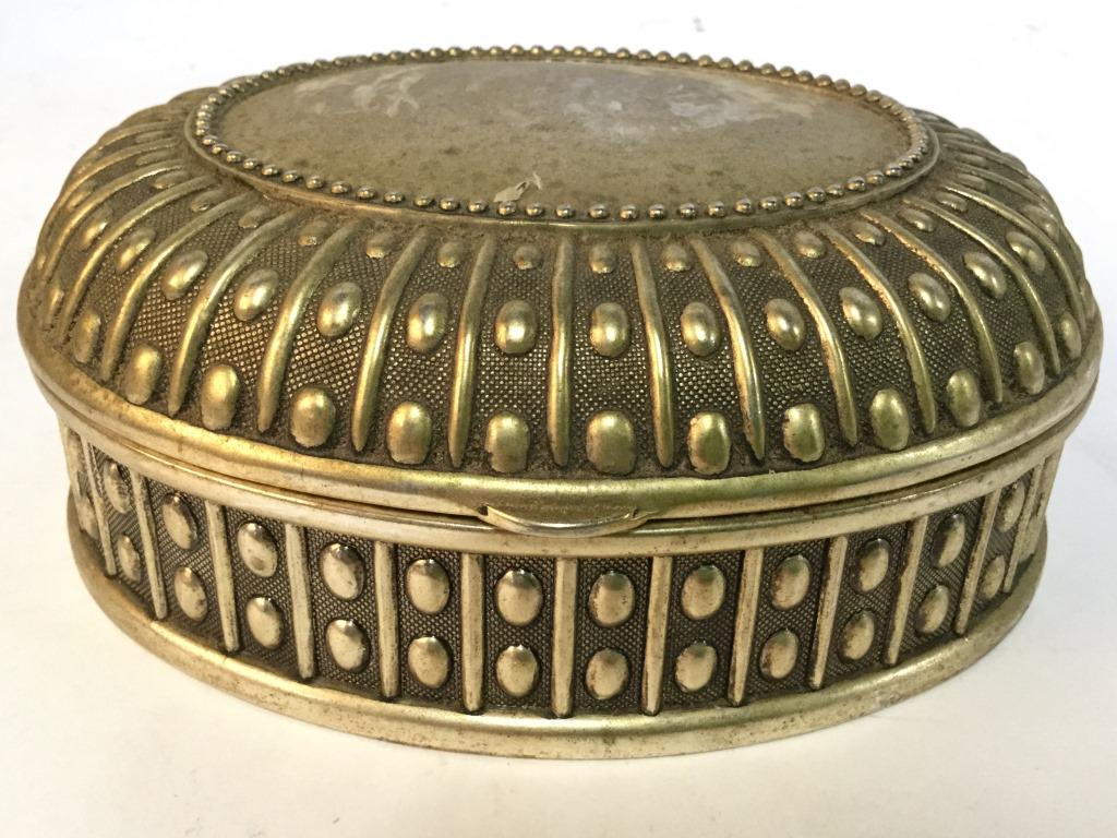 Gold Toned Lidded Metal Keepsake Box: Trinket Box is gold toned and oval shaped. Trinket Box has Lid. Piece measures approx 5.5 inches long 2 inches tall, 4.5 inches deep. trinket box, keepsake box, dresser box, jewelry box 6