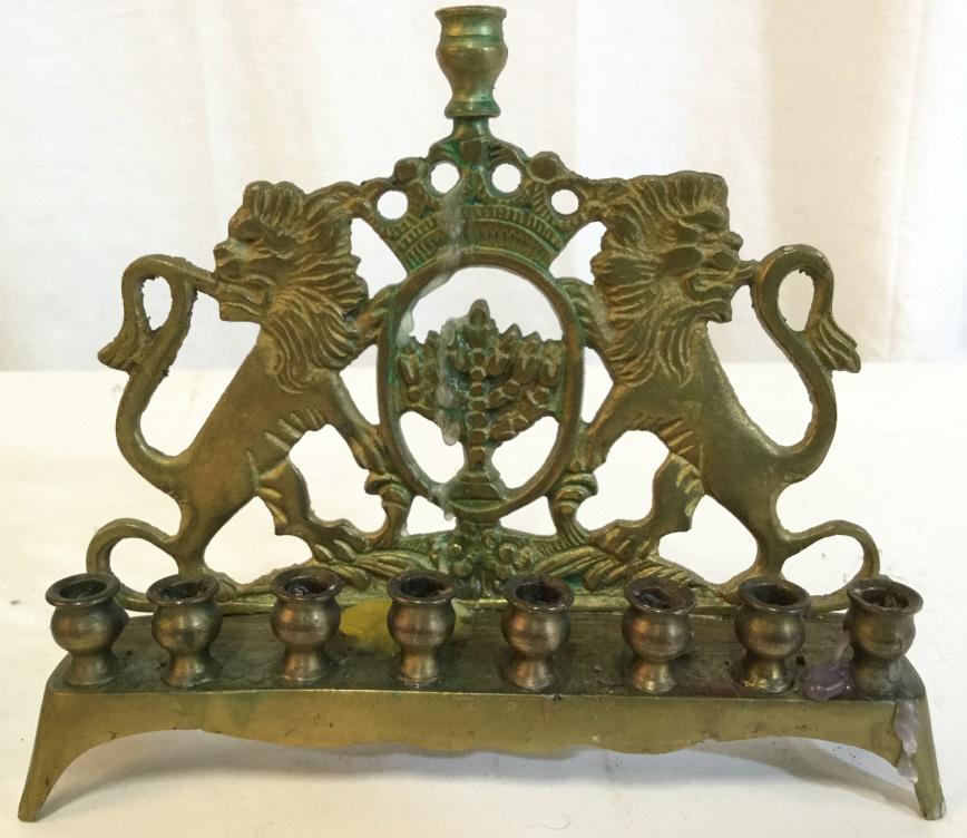 Gold Toned Metal Judaica Menorah: Menorah is gold toned, possibly brass. Piece has intricate Lion detail. Piece measures approx 8 inches long 7 inches tall. Contains wear and wax from previous use. judaica hebraica, decorative accesso