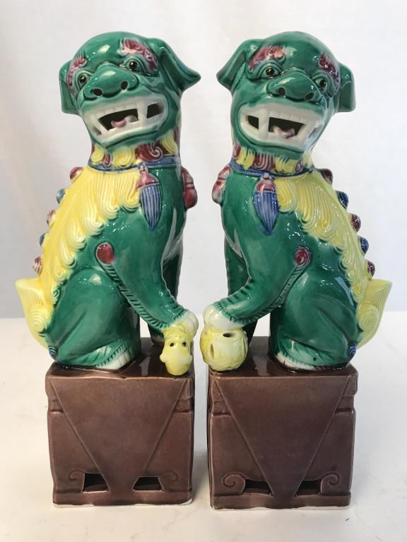 Pair Multi-Color Glazed Ceramic Foo Dog Sculptures: Pair of multi-color polychrome glazed ceramic foo dogs. 1 has paw on ball, the other has paw on small creature. Bright yellow, green, and rose taupe tones. Each is stamped 87 on underside, along with 