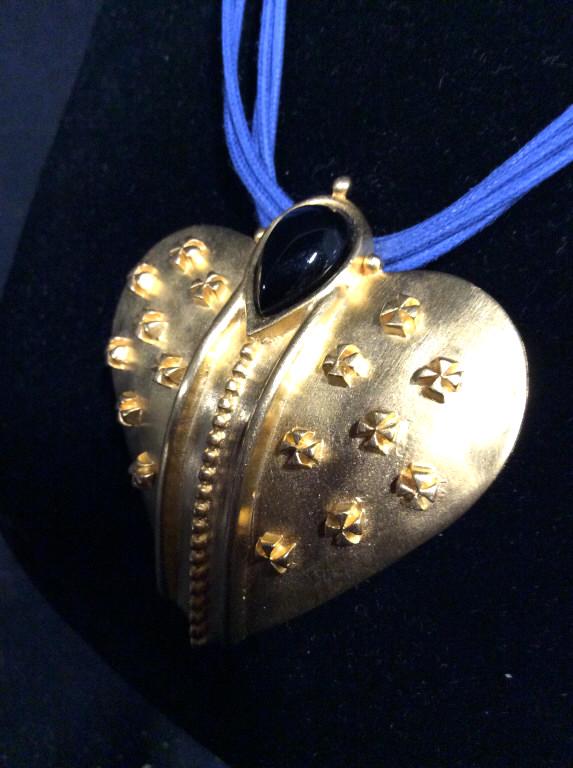 P.H. Heart Pendant Multi Strand Necklace: Heart shape gold tone pendant with raised designs and top center stone , possibly onyx. 5 strands on blue cord. Hangs 10 in. Cord app 15 in. Pendant measures 2 1/8 x 2 1/8 in. Reads P.H. on underside 