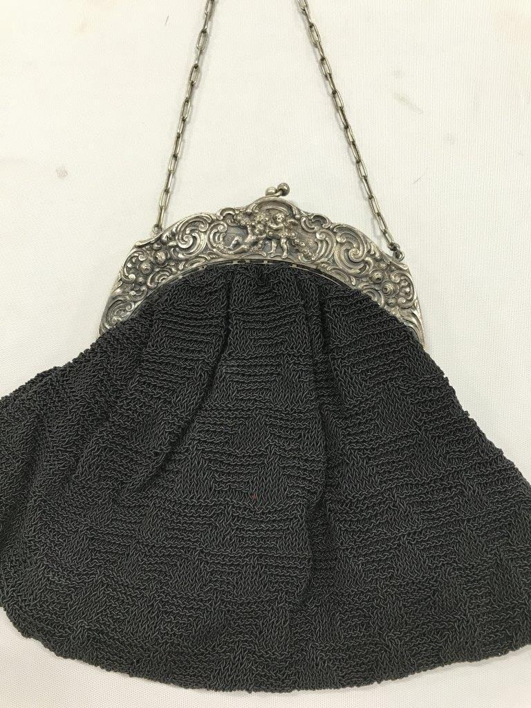 Antique Victorian Putti Repoussé Frame Handbag: antique Victorian/Edwardian silver toned ( possibly plated) framed evening bag /purse. Woven into square pattern, black on black. Body of purse measures 8 in. by 13 in., soft triangular form. Solid an