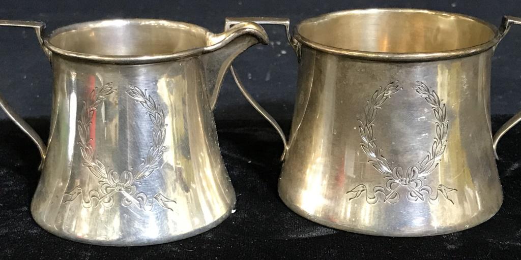 Lot 4, Vintage Sterling Silver Tableware: Creamer with etched wreathes and monogrammed. Marked STERLING with an emblem on underside. Measures 3.5 in. wide by 2 in. tall. Matching double handle sugar vessel/ bowl. 4.5 in. wide, 2 3/8 in. tall.