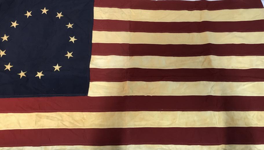 Collectible Betsy Ross Antique American Flag: Thirteen stars & stripes. Stars in circle. Embroidered. Two grommet holes, one bottom and one top of side. Flag measures 34.5 in. Vertical, 56 in. horizontal. Machine stitched. Heavy cotton. White fab