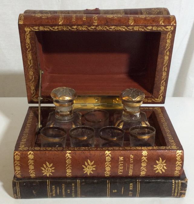 Vintage French Faux Book Decanter Set: Set of vintage, possible antique, Decanter sets. The glasses as well as the decanters are stored in false books. The books binding are decorated with gold toned embossed floral designs. The books are