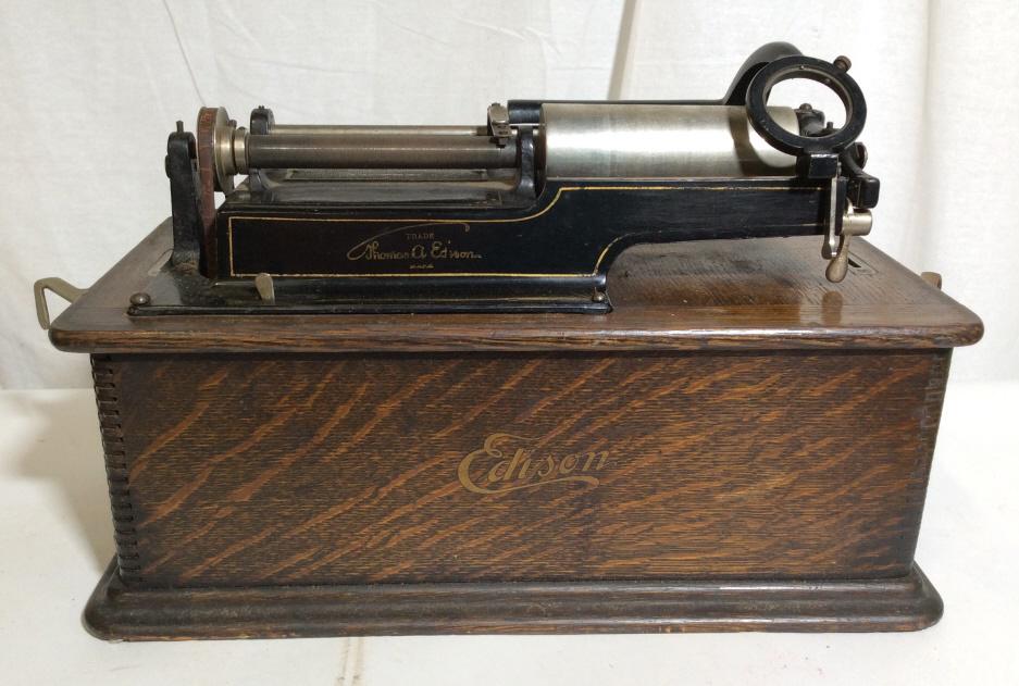 Antique EDISON Home Phonograph: Antique Edison home phonograph, encased in wood with a removable lid, handle attached for transport. The piece measure approx. 11.8 inches H, 16.12 inches wide, and has a depth of 8.75 inches. Does no