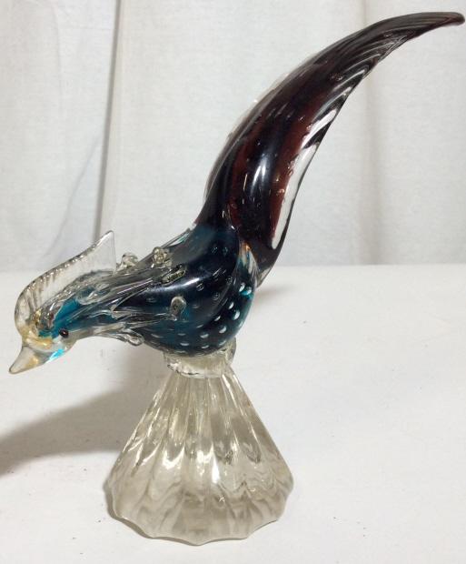 Venetian Glass Bird Statuette: Decorative Venetian Glass bird statue, piece originated in Murano Italy. The piece is colored in blue and purple tone. The piece measures approx 8 inches H, and 10.5 inches long, the base measures app