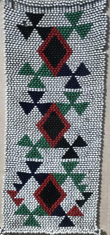 Antique Beaded Necklace, Framed: Antique beaded necklace, possibly African in origin. Necklace is fully beaded in tones of white, green, red, and blue. Necklace is mounted on linen and set behind glass in wood frame. Museum quality f