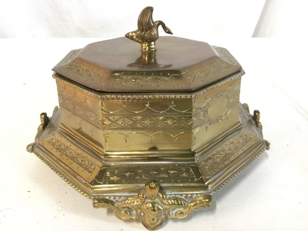 Gold Toned Metal Lidded Keepsake Box: Trinket Box is gold toned and metal, possibly brass. Piece has 4 ornately detailed feet. Piece contains lid with goose shaped handle. Trinket Box, Jewelry Box, Keepsake Box. Piece measures approx 7.5 